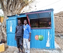 Dankouma Daoude & his friend outside his shop selling herbal tobacco for shisha pipes